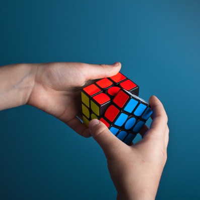 Systems and processes with hands holding a rubiks cube trying to solve it